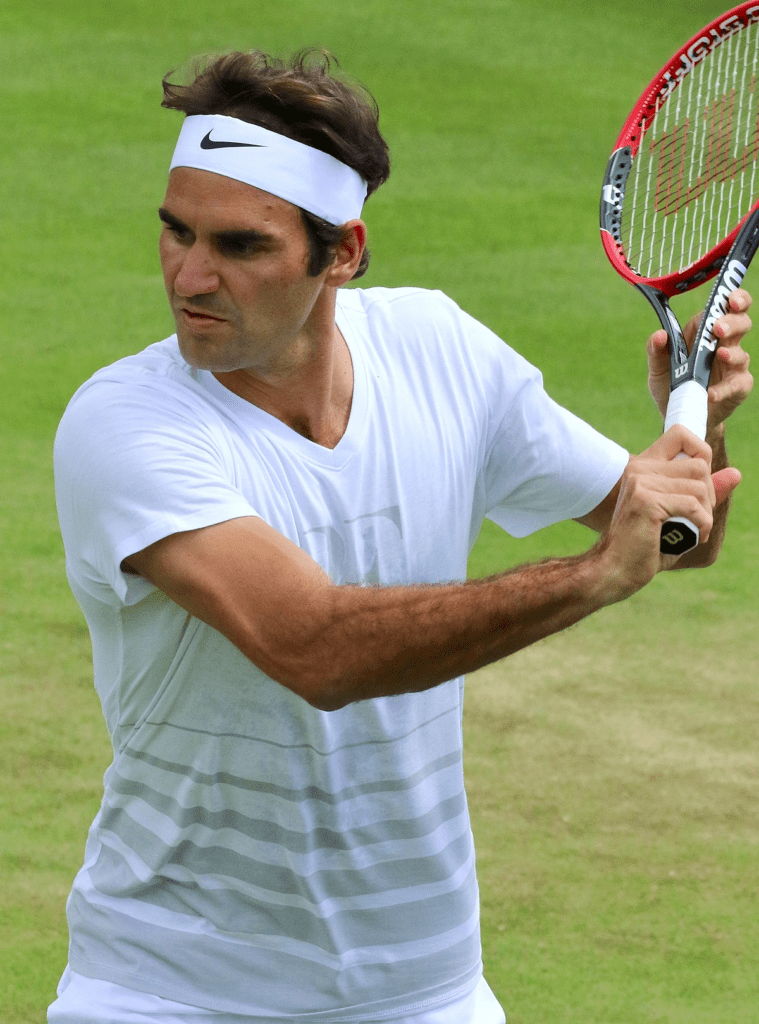Tenisista w trakcie wymachu rakietą w białej opasce - Roger Federer